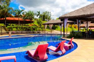 埃斯梅拉达斯Parque Do Avestruz Eco Resort的一个带红色椅子的游泳池,一个度假胜地