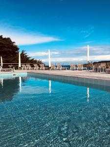 索宗卡迪纳百丽恩美酒店的一个带椅子的游泳池,背景是大海