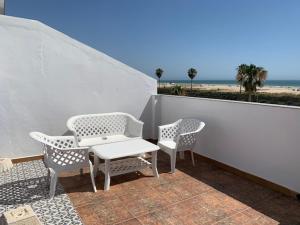 科尼尔-德拉弗龙特拉Hotel Playa Conil的海滩阳台配有两把椅子和一张桌子