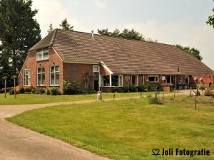 Ter ApelBuitengoed Het Achterdiep的一座带草地庭院的大型红砖房子