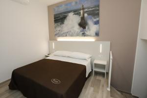 西维尔诺瓦·马尔凯Orchidea Rooms & Suites的卧室配有一张床,墙上挂有绘画作品