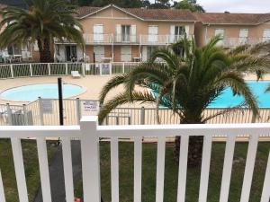 安格雷RESIDENCE LA CROISIERE- Appt Duplex 6 Personnes的棕榈树泳池前的白色围栏