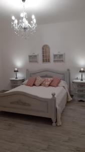 格罗塞托港Corte degli Angeli的白色卧室配有一张床和一个吊灯