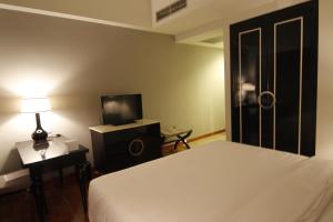 雅加达蒂拉德亚酒店的一间卧室配有一张床、一台电视和一盏灯