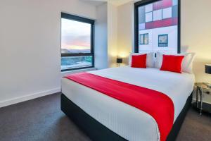 WantirnaMelbourne Knox Central Apartment Hotel Official的一间卧室配有一张带红色枕头的大床