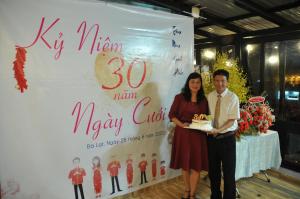 大叻Anh Trang Homestay的站在一块蛋糕的标志前的男女