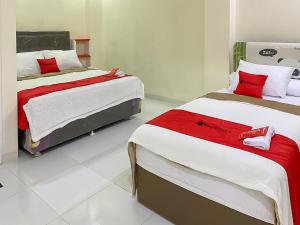 班达楠榜RedDoorz Syariah near PKOR Lampung的配有红色和白色床单的客房内的两张床