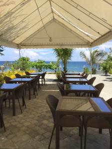 圣胡安EM Royalle Hotel & Beach Resort的一组桌子和椅子,背景是海洋