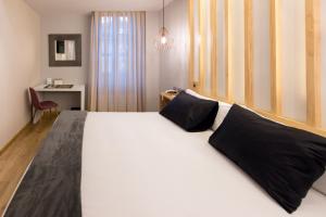 奥维多弗雷拉酒店的卧室配有一张带黑色枕头的大型白色床。