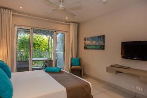 蒙舒瓦西蒙舒瓦西海滩度假公寓式酒店的一间卧室设有一张床、一台电视和一个窗口。