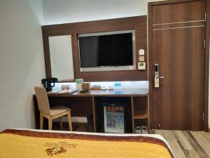 胡志明市Prague Saigon Airport Hotel的酒店客房设有一张桌子、一台电视和一张床