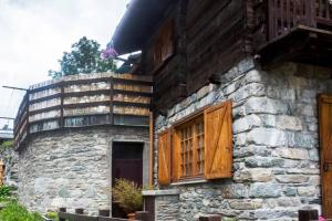 瓦托内切Chalet indipendente in centro a Valtournenche的一座石头建筑,设有木窗和阳台