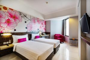 马卡萨favehotel - Pantai Losari Makassar的两张位于酒店客房的床,墙上挂着粉红色的鲜花