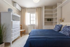 加的斯BLUE Atlantic Family Home by Cadiz4Rentals的白色卧室配有蓝色的床和架子
