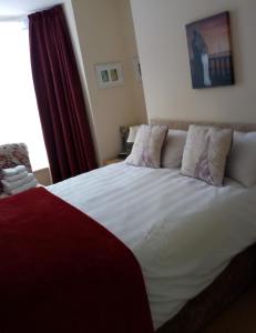 惠特比Cadame的卧室配有一张白色大床和红色窗帘