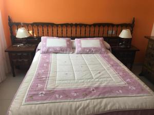 阿瑞斯A Postiña的一张大床,上面有粉红色的床单和枕头