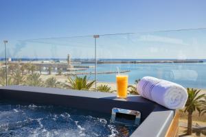 罗希姆诺Μuses Suites的在享有海滩景致的浴缸上享用饮品