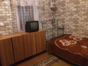 敖德萨Сдам комнату в гостевом домике的一间卧室配有一张床,并在橱柜上配有电视