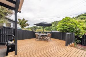 阿卡罗阿La Petite Maison - Akaroa Holiday Home的木甲板配有桌子和遮阳伞