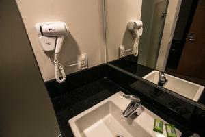 伊塔茹巴阿玛尼提柯尔酒店的一间带水槽的浴室和墙上的一部电话