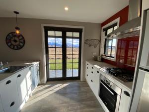 特威泽尔Pedalfish Cottages - Galaxy Views的厨房配有白色橱柜和美景门。