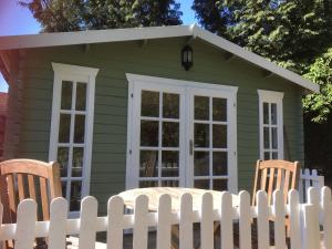 法纳姆Woodland Cabin With private Wood-Fired Hot-Tub的绿色房屋,设有白色围栏