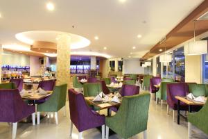 巴厘巴板巴厘巴板瑞士博林酒店的餐厅设有紫色和绿色的椅子和桌子