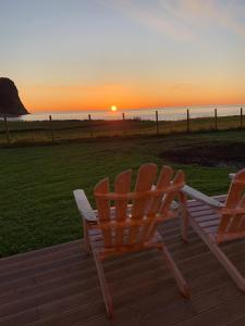 UnnstadUnstad Arctic Resort的两把椅子坐在甲板上,欣赏日落美景