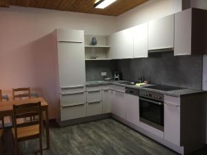 特里森贝格里特利公寓的厨房配有白色橱柜、桌子和桌子