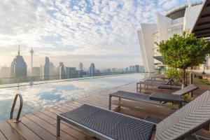 吉隆坡KLCC Regalia Suites Infinity Pool Kuala Lumpur的一个带椅子的屋顶游泳池,享有城市美景