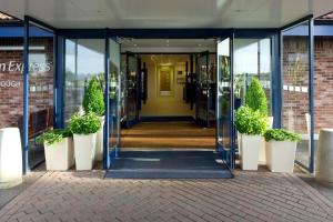 彼得伯勒快捷假日彼得伯勒酒店的一座有盆栽植物的建筑的开放式玻璃门