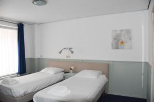 乌登Hotel Verhoeven的客房设有两张床和窗户。