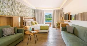 韦瑞洛纳Dolce by Wyndham Athens Attica Riviera的酒店客房,设有一张床和两张绿色沙发