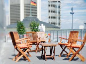 美因河畔法兰克福Mövenpick Hotel Frankfurt City Messe的阳台上的一组椅子和一张桌子