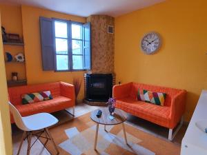 欧德鲁佐Pensión O Muiño的客厅配有2张橙色沙发和1个时钟