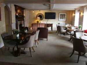皇家伍顿巴西特天使在伍顿巴西特酒店的一间带桌椅和钢琴的餐厅