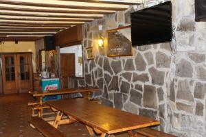 坎弗兰克Albergue-Refugio Sargantana的客房设有两张木桌和石墙上的电视。