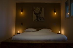 波利尼Aux Platanes的一间卧室配有一张带两个蜡烛的大型白色床。