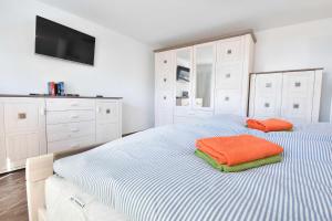 KamminkeFerienhaus Insel-Paradies的白色卧室配有带橙色枕头的床