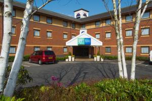 埃克塞特Holiday Inn Express Exeter East, an IHG Hotel的前面有停车位的大楼