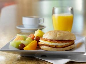 圣安东尼奥圣安东尼奥机场/鲗鱼市场凯悦嘉轩酒店的盘子,夹三明治,水果和一杯橙汁