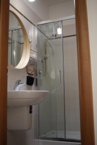 莫诺波利Serena GuestHouse的一间带玻璃淋浴和水槽的浴室