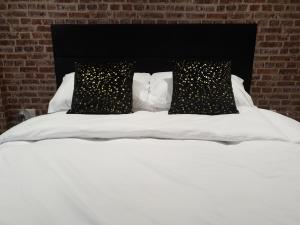 布恩The Snug Bourne的一张带两个黑色枕头的白色床
