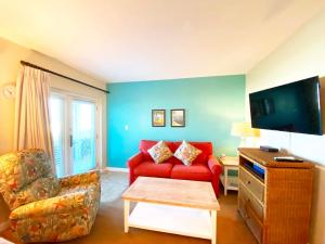 圣徒皮特海滩海畔卡米洛特酒店的客厅配有红色沙发和电视