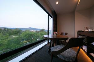 京都Riverte Kyoto Kamogawa的客房设有桌椅和大窗户。