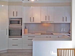 浅滩湾Adriana 3 unit with a backyard的厨房配有白色橱柜和炉灶烤箱。