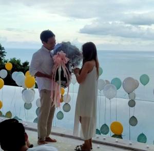 查汶BelVillas-Award Winning SeaView Luxury Villas的男子和女子在气球前抱着花束