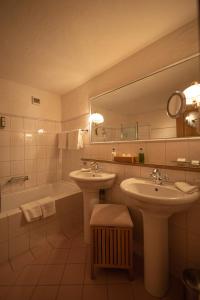 格施塔德Hotel Alpenrose mit Gourmet-Restaurant Azalée的浴室设有2个水槽、浴缸和镜子