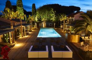 圣特罗佩Villa Cosy, hotel & spa的棕榈树的游泳池的夜晚图像