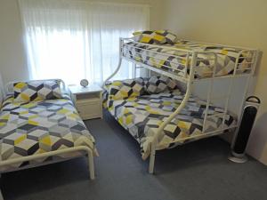 浅滩湾Adriana 3 unit with a backyard的一间卧室配有一张双层床、一张床和一张双层床。